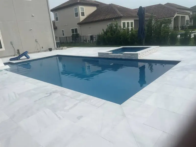 Rectangular pool with a raised spa, Glass tile spillway, white paver deck