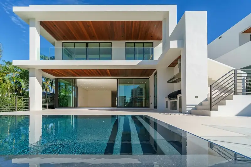 Modern rectangular pool beside a two-story home with a covered patio